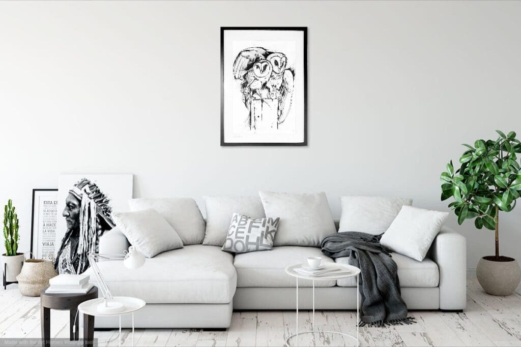 A white couch with pillows and a coffee table and black and white drawing of 2 owls