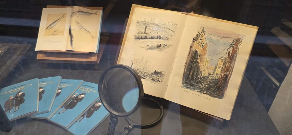 Display case of historic sketchbooks with ink and watercolour pages in Bellano