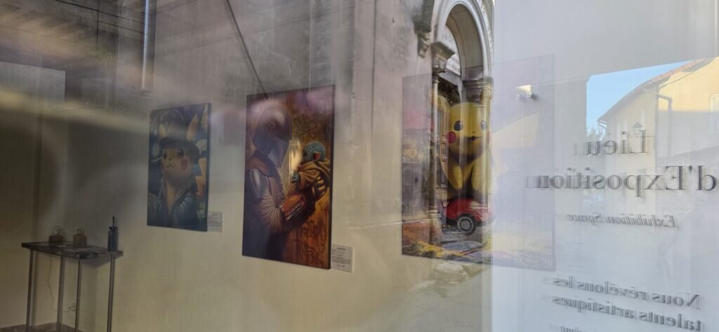 Gallery window at dawn in L'Isle-sur-la-Sorgue with three contemporary paintings hanging inside and the words Lieu d'Exposition etched on the glass