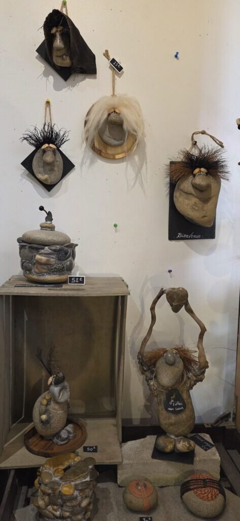 River stones made into small characters with raffia hair, mounted on slate and wood, with chalkboard price tags in a shop in L'Isle-sur-la-Sorgue