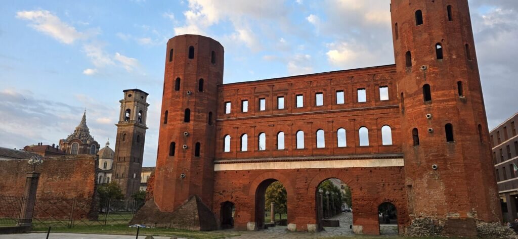 The two tall red-brick towers of the Porta Palatina, a Roman gate in Turin, glowing in the first light of dawn