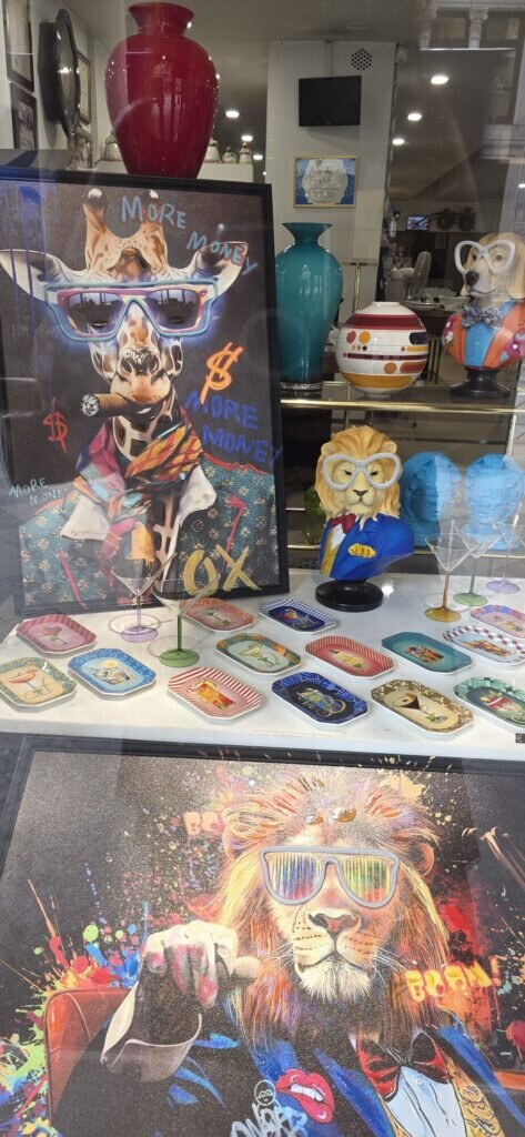 A Turin shop window filled with brightly coloured pop art prints of animals in sunglasses, painted vases and small decorated trays