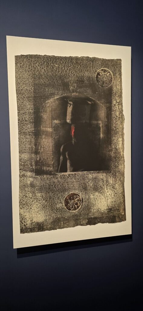 A dark framed print with a single red panel breaking through black tones