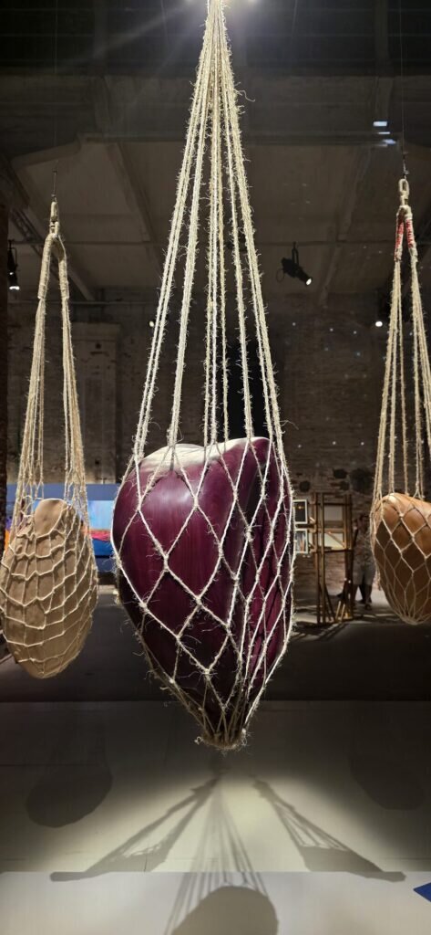 Large burgundy and gold globes cradled in rope netting, hanging the length of an old industrial hall