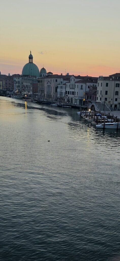 Dawn over the Grand Canal in Venice with the green copper dome of San Simeone Piccolo catching pink light