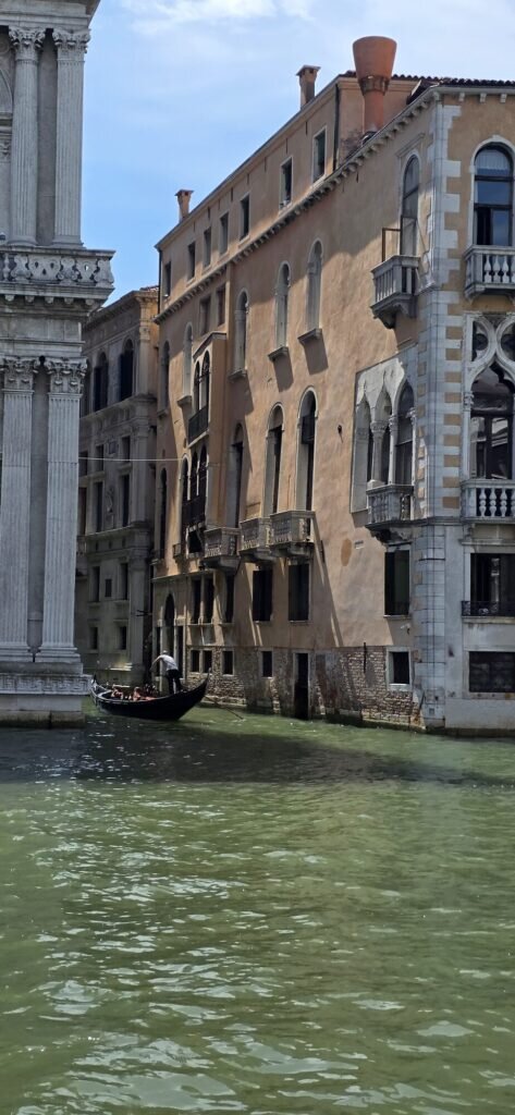 A lone gondola sliding through warm light on a quiet Venetian canal
