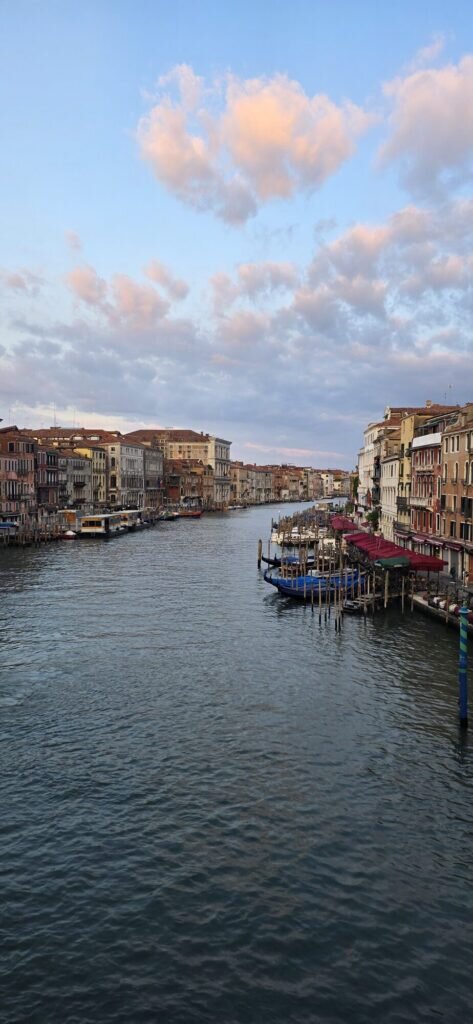 The Grand Canal in Venice at dawn seen from the Rialto bridge, pink clouds over the palaces and moored boats
