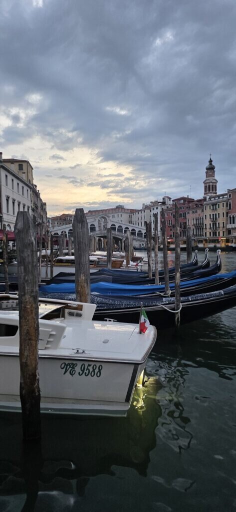 Dawn at the Rialto in Venice, gondolas under blue covers along the Grand Canal with the Rialto bridge behind