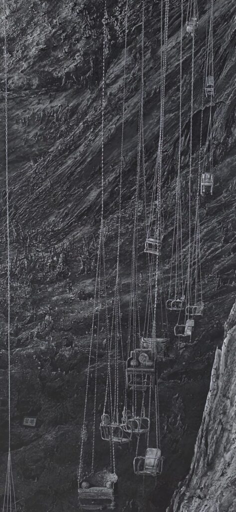 Large black and white photograph of a sheer rock face with dozens of small seats and baskets hanging from long chains down the cliff